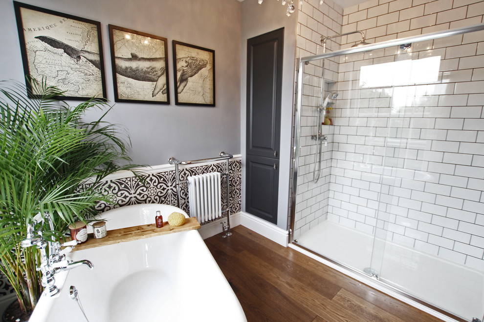 Mittelgroßes Stilmix Badezimmer mit grauen Schränken, freistehender Badewanne, offener Dusche, Metrofliesen, grauer Wandfarbe, dunklem Holzboden, braunem Boden und Schiebetür-Duschabtrennung