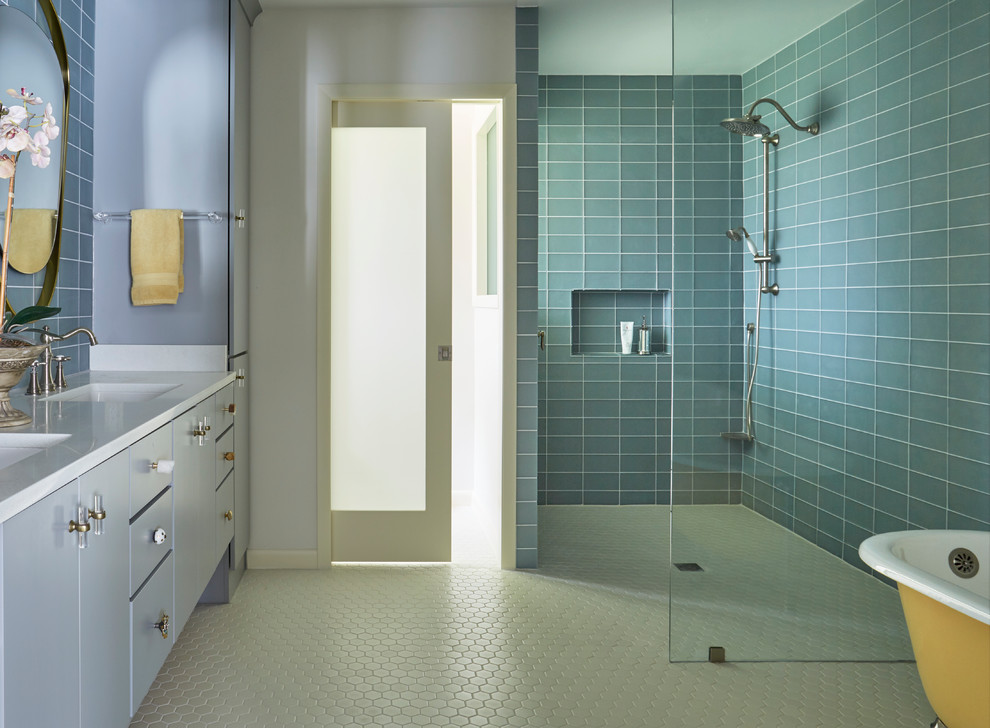 Cette image montre une grande salle de bain principale bohème avec un placard à porte plane, des portes de placard grises, une baignoire sur pieds, une douche à l'italienne, WC séparés, un carrelage bleu, un carrelage en pâte de verre, un mur bleu, un sol en carrelage de porcelaine, un lavabo encastré, un plan de toilette en quartz modifié, un sol blanc, aucune cabine et un plan de toilette blanc.