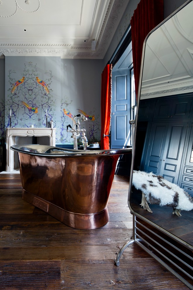 Idée de décoration pour une salle de bain bohème avec une baignoire indépendante, un mur bleu, parquet foncé et un sol marron.