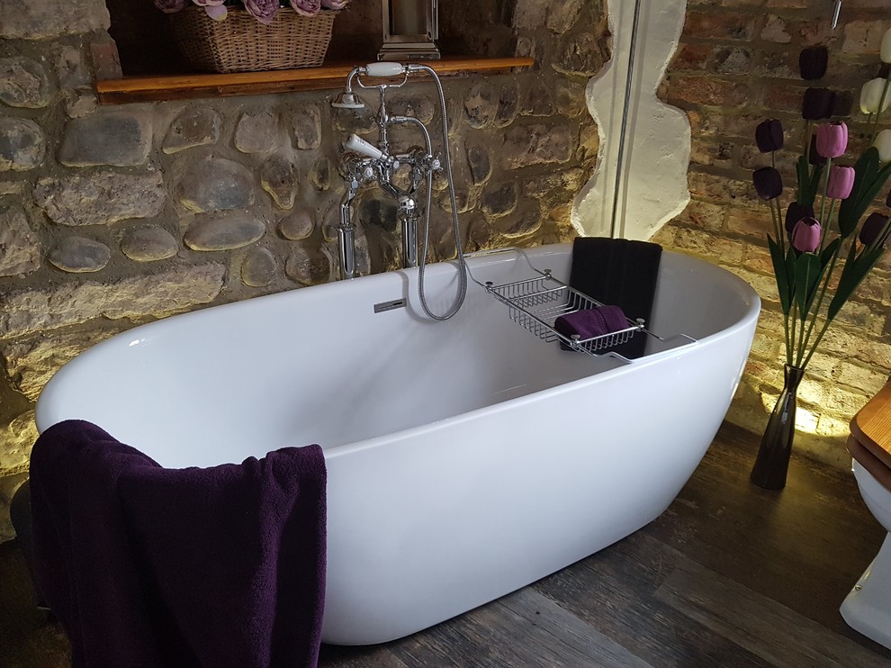 Photo of a medium sized bohemian family bathroom in Other with open cabinets, medium wood cabinets, a freestanding bath, multi-coloured tiles, stone slabs, white walls, vinyl flooring, a vessel sink, wooden worktops, brown floors and a two-piece toilet.