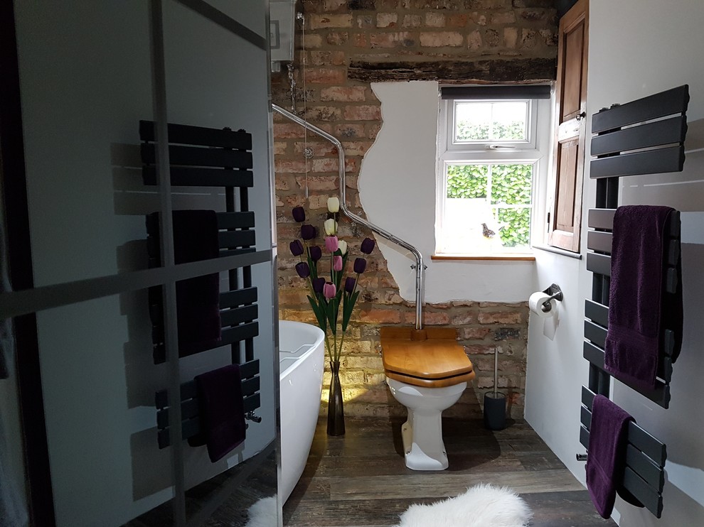 Medium sized eclectic family bathroom in Other with open cabinets, medium wood cabinets, a freestanding bath, multi-coloured tiles, stone slabs, white walls, vinyl flooring, a vessel sink, wooden worktops, brown floors and a two-piece toilet.
