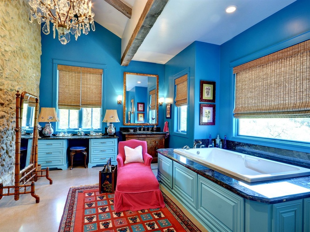 Cette photo montre une grande salle de bain principale éclectique avec un placard avec porte à panneau surélevé, des portes de placard bleues, une baignoire posée, un carrelage beige, un mur bleu, sol en béton ciré, un plan de toilette en granite et un sol gris.