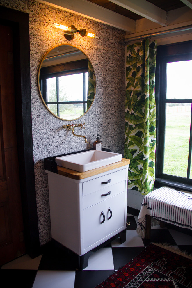 Exemple d'une grande salle de bain principale nature avec un placard en trompe-l'oeil, une baignoire sur pieds, une douche ouverte, WC à poser, un carrelage noir et blanc, des carreaux de céramique, un mur rose, un sol en carrelage de céramique, une vasque, un plan de toilette en bois, un sol noir, une cabine de douche avec un rideau et un plan de toilette marron.