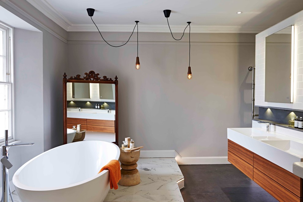 На фото: главная ванная комната среднего размера в стиле фьюжн с подвесной раковиной, отдельно стоящей ванной, белой плиткой, серыми стенами и полом из керамогранита с