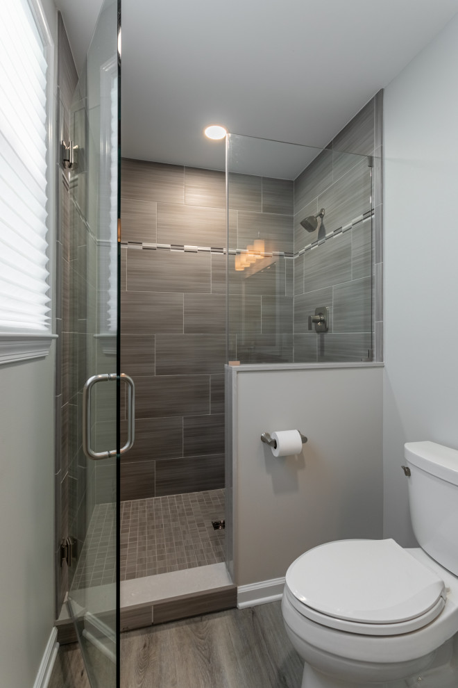 Exempel på ett mellanstort klassiskt vit vitt badrum, med skåp i shakerstil, vita skåp, en dusch i en alkov, en toalettstol med hel cisternkåpa, vit kakel, keramikplattor, blå väggar, vinylgolv, ett undermonterad handfat, granitbänkskiva, brunt golv och dusch med skjutdörr