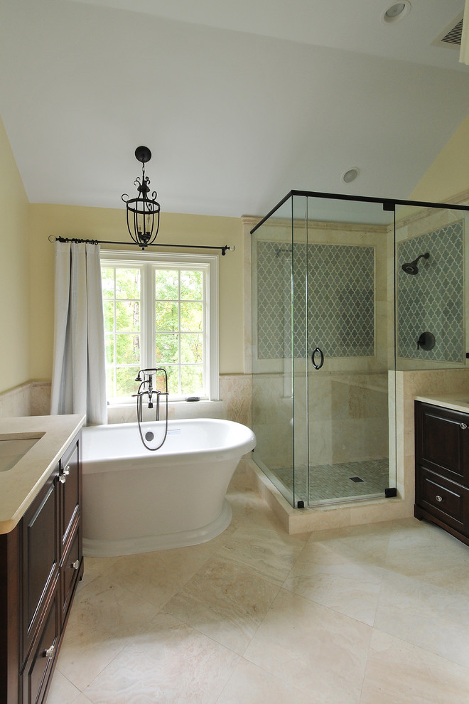 Ejemplo de cuarto de baño tradicional con bañera exenta, paredes amarillas y baldosas y/o azulejos de travertino