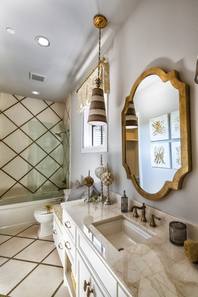 Inspiration for a medium sized bohemian shower room bathroom in Dallas with recessed-panel cabinets, white cabinets, white tiles, beige tiles, marble tiles, white walls, mosaic tile flooring, a submerged sink, marble worktops, an alcove bath, a shower/bath combination and a two-piece toilet.