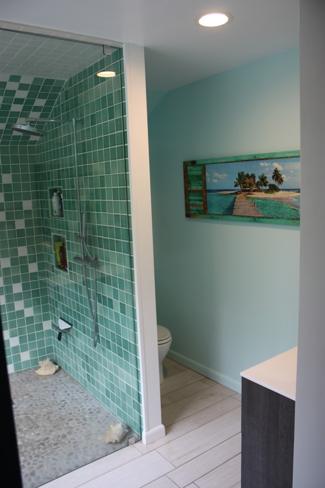 Inspiration pour une salle de bain principale design de taille moyenne avec un placard à porte plane, des portes de placard grises, un plan de toilette en surface solide, un carrelage vert, un mur vert, un sol en galet, une douche ouverte, des carreaux de porcelaine et un lavabo suspendu.