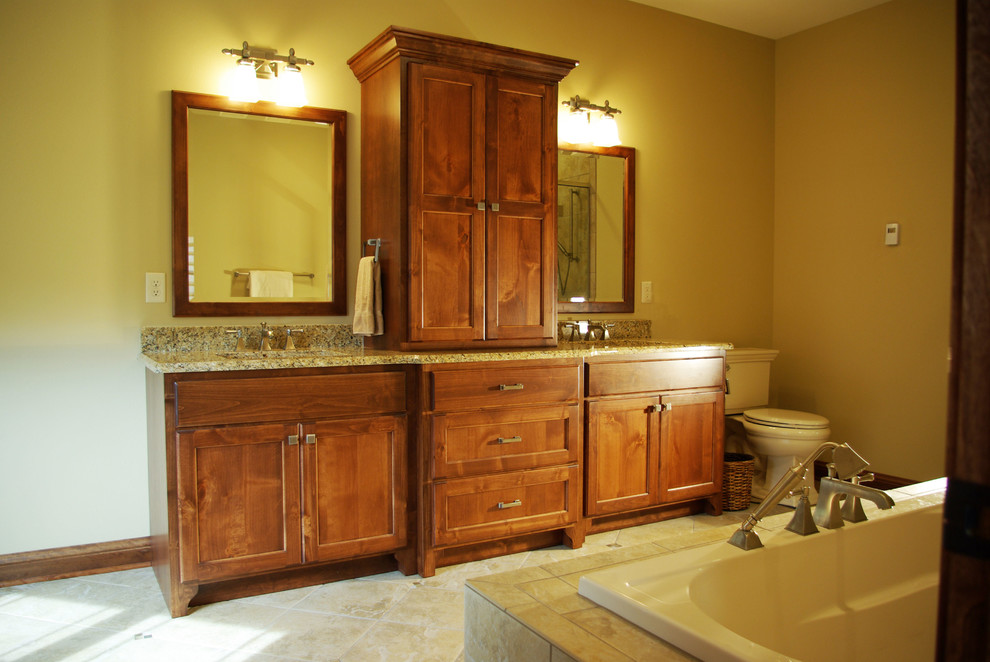 Design ideas for a medium sized classic ensuite bathroom in Milwaukee with an integrated sink, recessed-panel cabinets, medium wood cabinets, a built-in bath, a corner shower, a one-piece toilet, yellow walls, stone tiles, porcelain flooring and granite worktops.