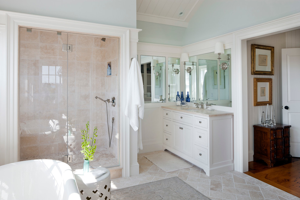 Aménagement d'une douche en alcôve bord de mer avec un lavabo encastré, un placard à porte shaker, des portes de placard blanches, une baignoire indépendante, un carrelage beige, un mur bleu et un sol beige.
