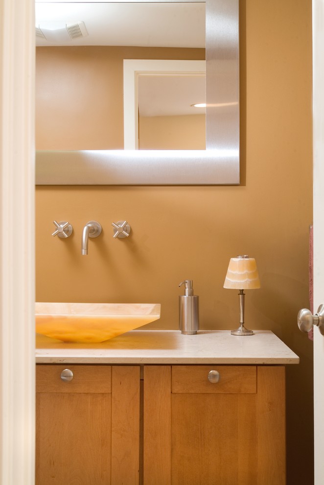 Ejemplo de cuarto de baño actual pequeño con lavabo sobreencimera, armarios estilo shaker, puertas de armario de madera clara, encimera de piedra caliza, sanitario de una pieza, paredes beige y suelo de madera clara