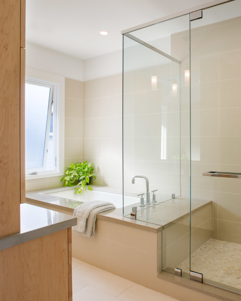Modern inredning av ett badrum, med en dusch i en alkov, beige kakel och ett undermonterat badkar
