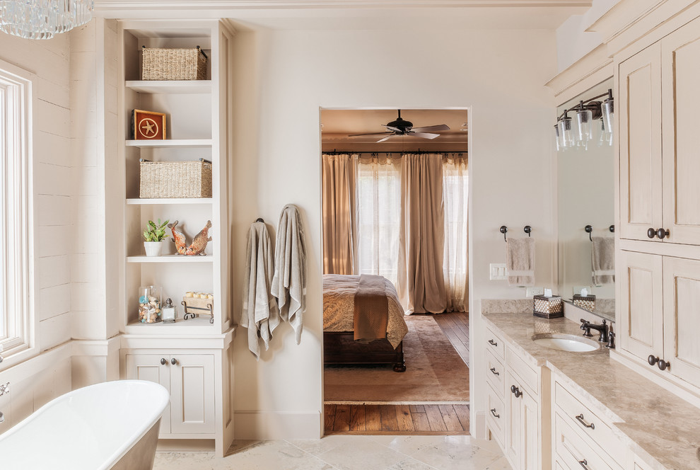 Cette image montre une salle de bain principale avec un placard à porte shaker, des portes de placard beiges, une baignoire indépendante et un mur beige.