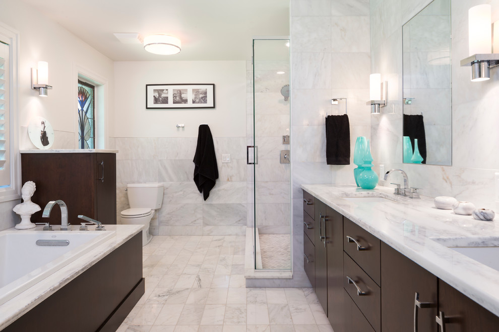 Cette image montre une grande salle de bain principale minimaliste en bois foncé avec un lavabo encastré, un placard à porte plane, un plan de toilette en marbre, une baignoire posée, une douche d'angle, un carrelage gris, un carrelage de pierre, un mur blanc et un sol en marbre.