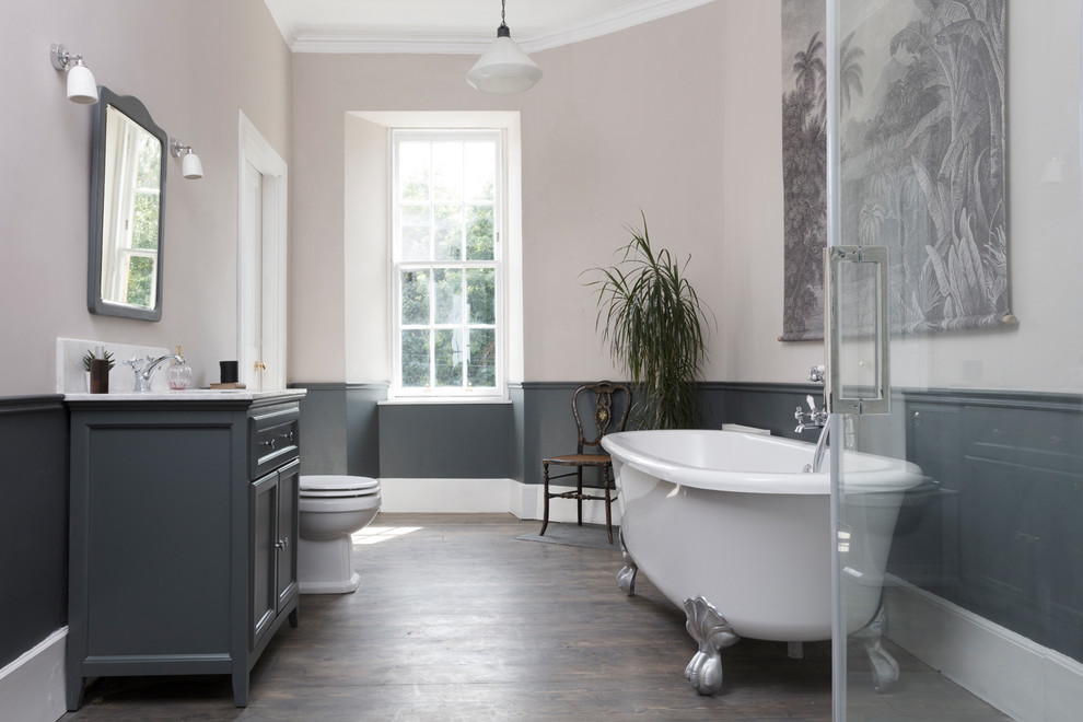 Photo of a medium sized classic family bathroom in Edinburgh with grey cabinets, a claw-foot bath, a two-piece toilet, white tiles, marble tiles, grey walls, dark hardwood flooring, a console sink, marble worktops, grey floors, white worktops, a dado rail and recessed-panel cabinets.