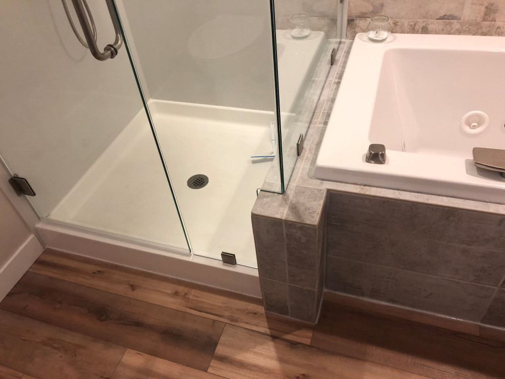 Design ideas for a medium sized contemporary ensuite bathroom in Seattle with shaker cabinets, grey cabinets, a built-in bath, a corner shower, a two-piece toilet, grey tiles, porcelain tiles, white walls, vinyl flooring, a submerged sink, engineered stone worktops, brown floors, a hinged door and white worktops.