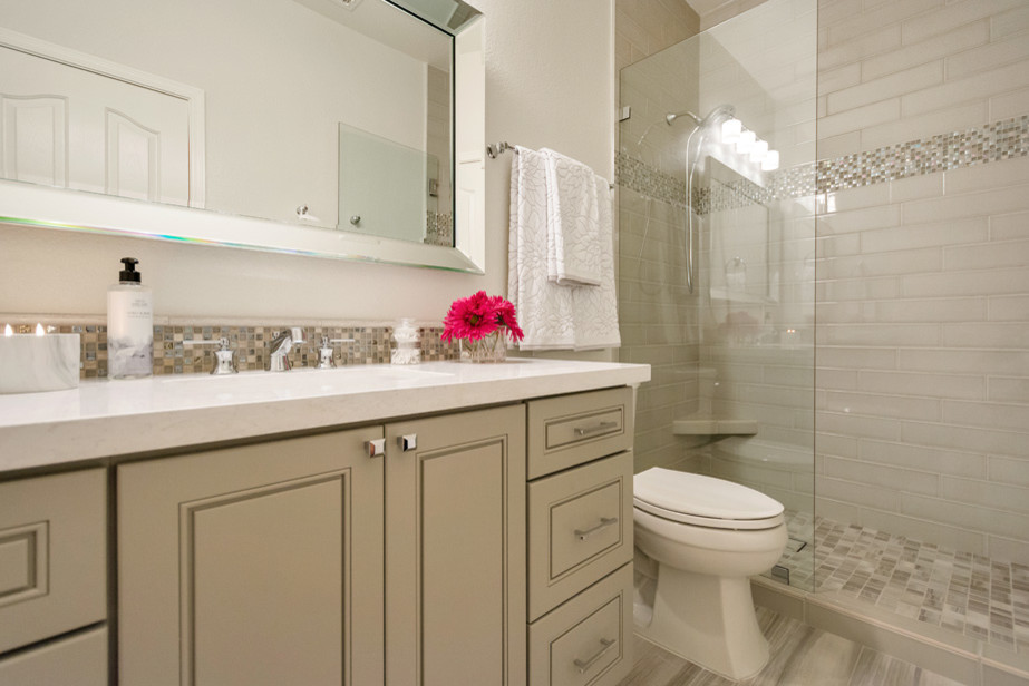 Пример оригинального дизайна: ванная комната среднего размера в стиле неоклассика (современная классика) с фасадами с выступающей филенкой, серыми фасадами, душем в нише, серой плиткой, плиткой кабанчик, серыми стенами, полом из керамической плитки, душевой кабиной, врезной раковиной, столешницей из кварцита, серым полом, душем с распашными дверями и раздельным унитазом