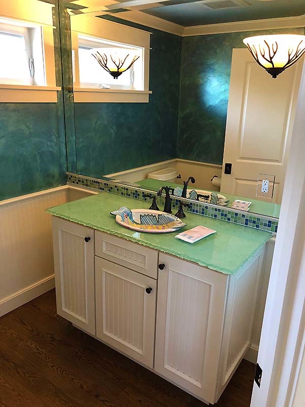 На фото: ванная комната с зелеными фасадами и столешницей из известняка