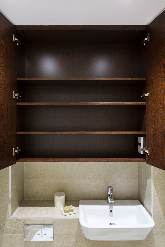 Immagine di una stanza da bagno design di medie dimensioni con WC sospeso, piastrelle beige e lavabo da incasso