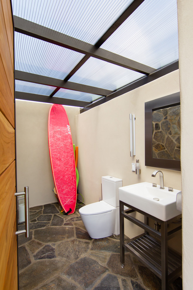 Bild på ett mellanstort funkis badrum, med ett konsol handfat, beige väggar, öppna hyllor, en toalettstol med separat cisternkåpa, flerfärgad kakel, stenkakel och skiffergolv