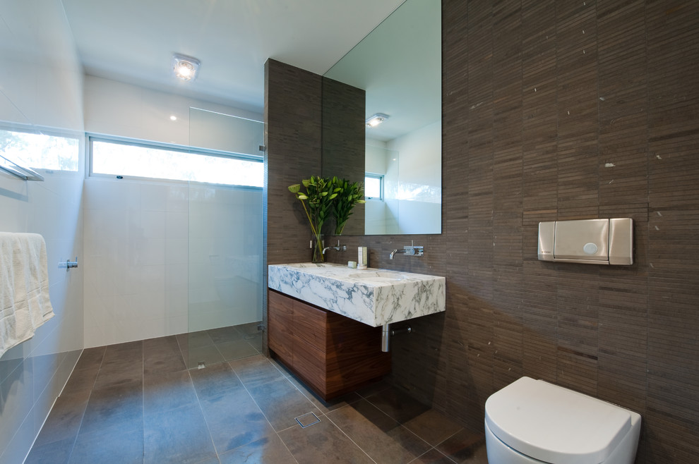 Design ideas for a small contemporary ensuite bathroom in Adelaide with a submerged sink, flat-panel cabinets, medium wood cabinets, marble worktops, an alcove shower, a one-piece toilet, brown tiles, porcelain tiles, brown walls and porcelain flooring.