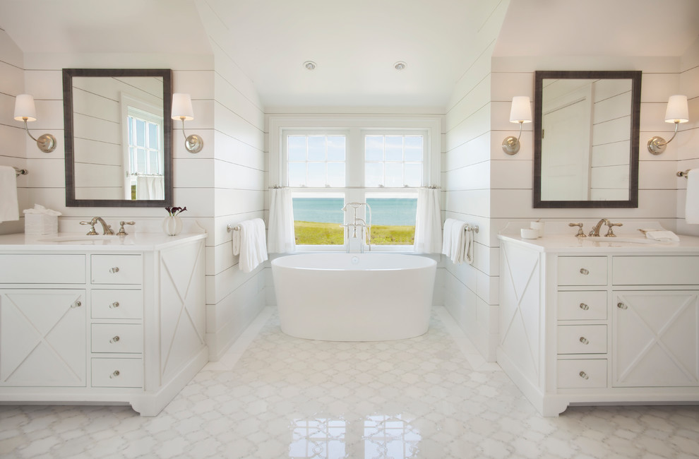 Пример оригинального дизайна: главная ванная комната в морском стиле с белыми фасадами, отдельно стоящей ванной, белыми стенами и белым полом
