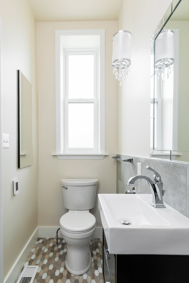 Modern inredning av ett litet badrum med dusch, med möbel-liknande, svarta skåp, en hörndusch, en toalettstol med hel cisternkåpa, grå kakel, stenhäll, vita väggar, klinkergolv i keramik, ett piedestal handfat, bänkskiva i akrylsten, brunt golv och med dusch som är öppen