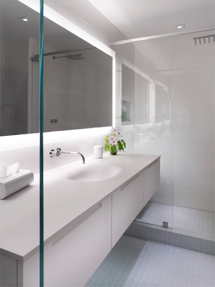 Exempel på ett stort modernt vit vitt en-suite badrum, med ett integrerad handfat, släta luckor, vita skåp, en dusch i en alkov, mosaikgolv, bänkskiva i akrylsten, grå kakel, keramikplattor, vita väggar och grått golv