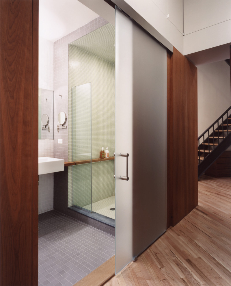 Immagine di una stanza da bagno moderna con lavabo sospeso, doccia alcova, piastrelle grigie e pareti bianche