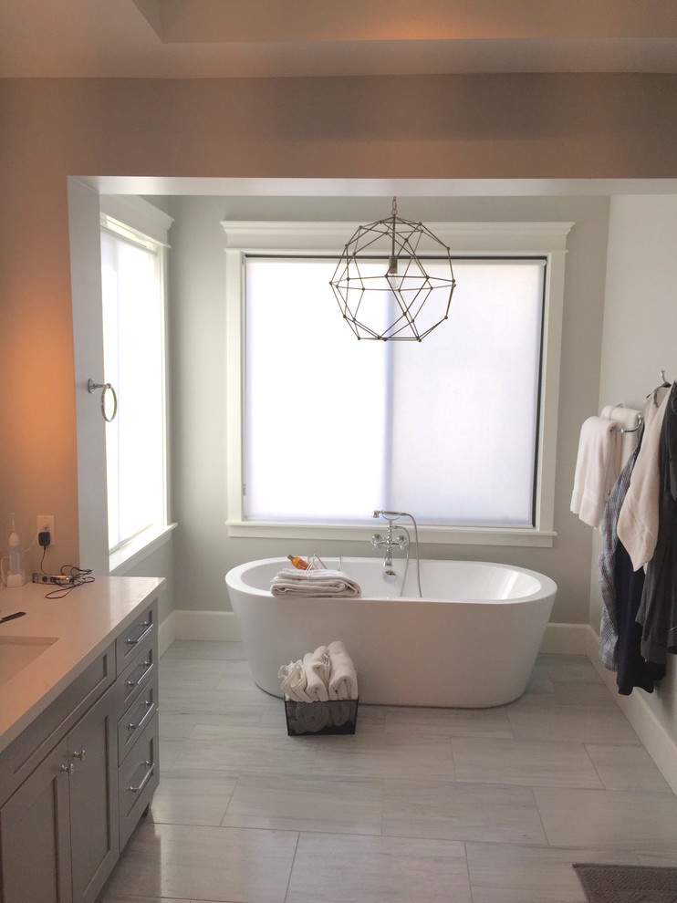 Immagine di una stanza da bagno padronale contemporanea di medie dimensioni con ante in stile shaker, ante grigie, vasca freestanding, pareti grigie, pavimento con piastrelle in ceramica, lavabo sospeso e pavimento grigio