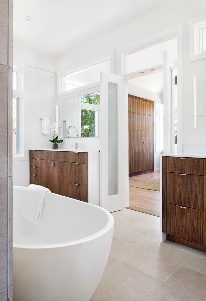 Modern inredning av ett stort en-suite badrum, med släta luckor, skåp i mörkt trä, ett fristående badkar, vita väggar, klinkergolv i porslin, ett undermonterad handfat och beiget golv