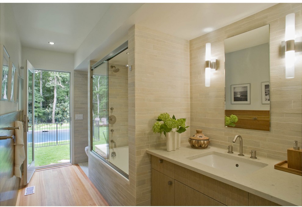 Ispirazione per una stanza da bagno design con piastrelle in pietra e lavabo sottopiano