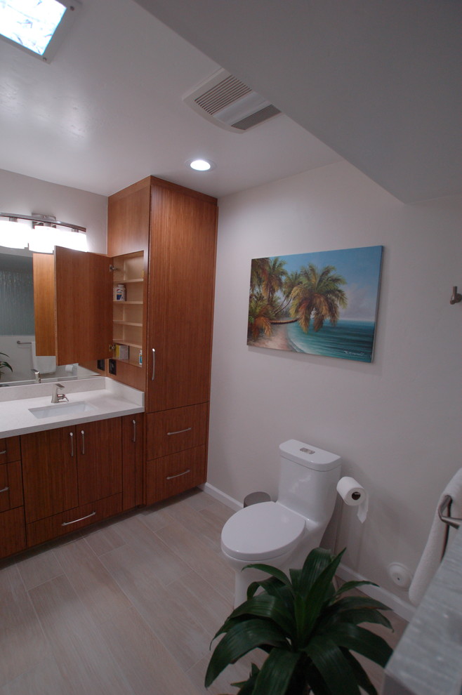 Inspiration for a medium sized coastal ensuite bathroom in San Diego with brown cabinets, a built-in shower, a one-piece toilet, blue tiles, glass tiles, white walls, porcelain flooring, a submerged sink, quartz worktops, beige floors and an open shower.