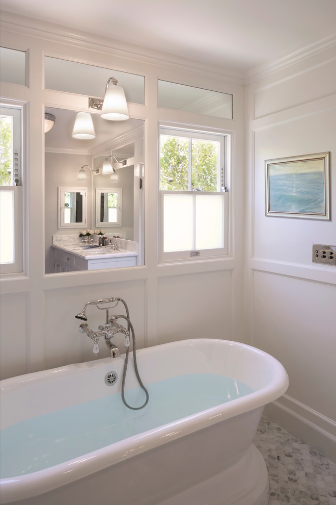 Cette image montre une douche en alcôve principale traditionnelle de taille moyenne avec un lavabo encastré, un placard avec porte à panneau encastré, un plan de toilette en marbre, une baignoire indépendante, un mur gris et un sol en marbre.