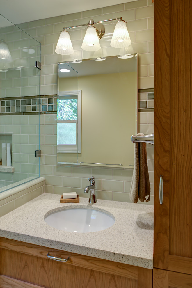 На фото: маленькая ванная комната в классическом стиле с врезной раковиной, фасадами в стиле шейкер, фасадами цвета дерева среднего тона, столешницей из искусственного кварца, угловым душем, раздельным унитазом, зеленой плиткой, керамической плиткой, желтыми стенами, полом из мозаичной плитки, белым полом, душем с раздвижными дверями, душевой кабиной, бежевой столешницей, нишей, сиденьем для душа, тумбой под одну раковину и встроенной тумбой для на участке и в саду