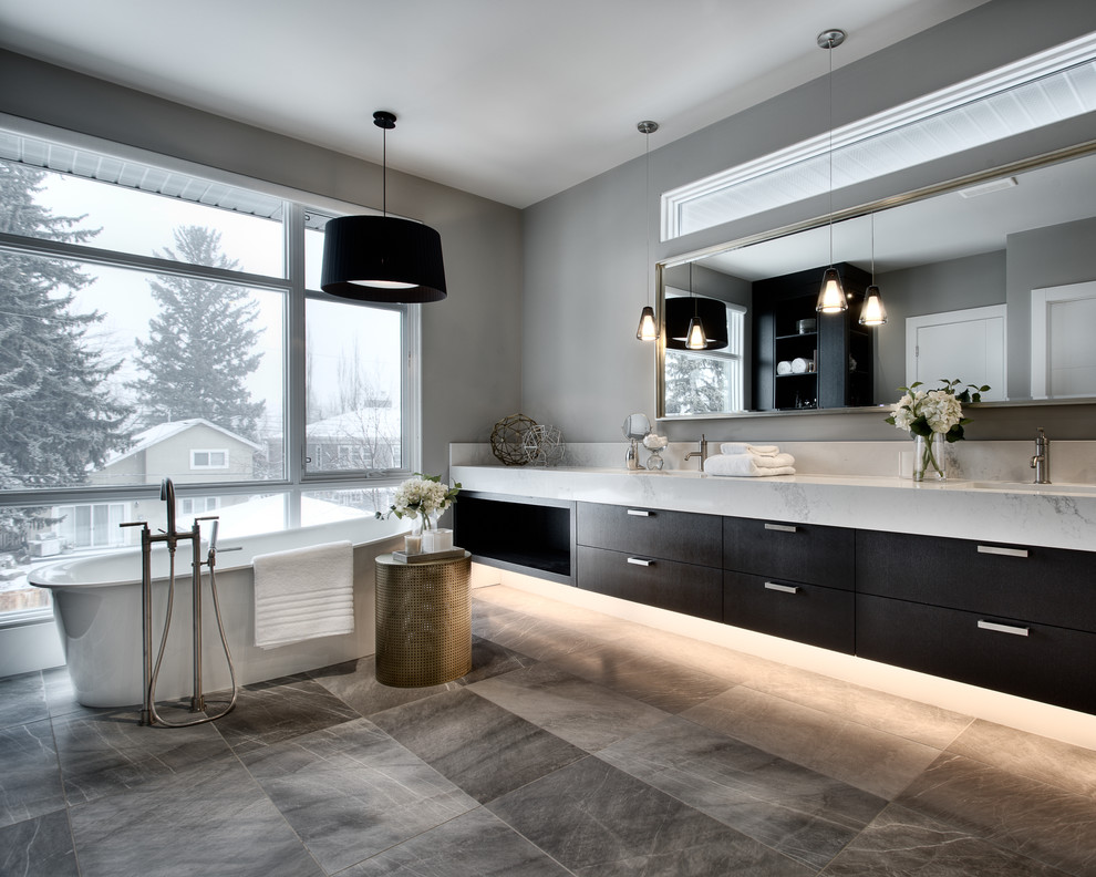 Foto de cuarto de baño gris y negro contemporáneo con armarios con paneles lisos, puertas de armario de madera en tonos medios, bañera exenta y paredes grises