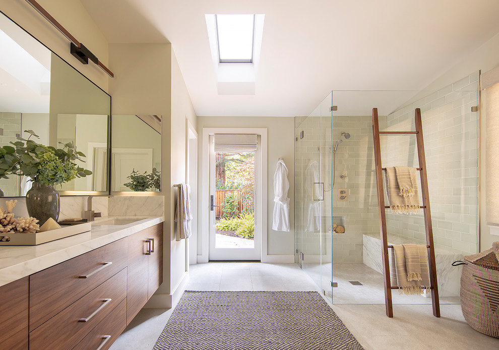 Cette photo montre une salle de bain principale tendance en bois brun avec un placard à porte plane, une douche d'angle, un carrelage vert, un mur beige, un lavabo encastré, un sol gris, une cabine de douche à porte battante et un plan de toilette blanc.