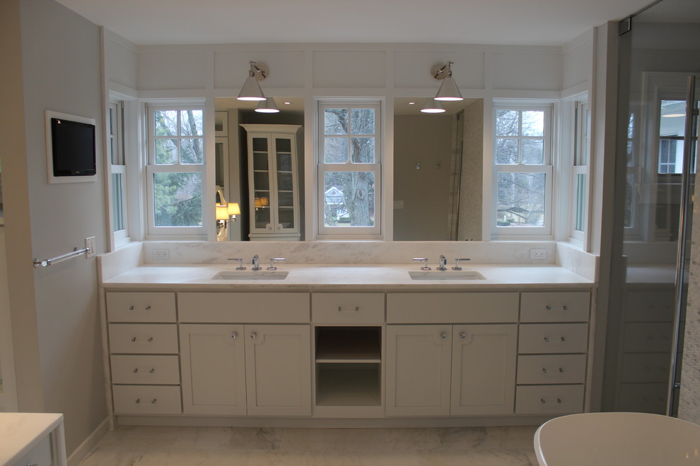 Inredning av ett klassiskt en-suite badrum, med släta luckor, vita skåp, marmorbänkskiva, ett fristående badkar, vit kakel och marmorgolv