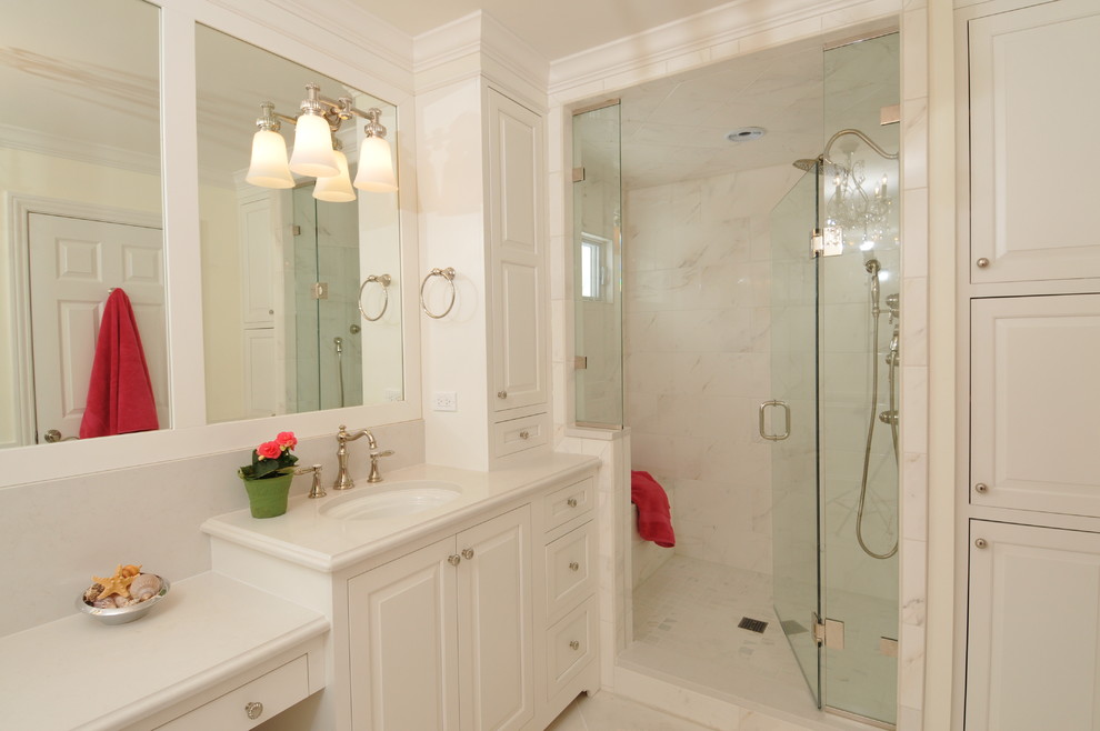 Aménagement d'une salle de bain classique avec un lavabo encastré, un placard avec porte à panneau surélevé, des portes de placard blanches et un carrelage blanc.