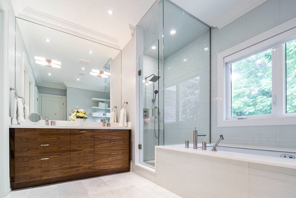 Medium sized modern ensuite bathroom in Toronto with flat-panel cabinets, dark wood cabinets, a submerged bath, a corner shower, blue walls, engineered stone worktops, marble flooring, a submerged sink, glass tiles, white floors and a hinged door.