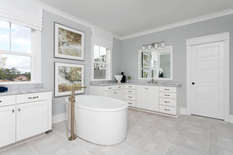 Example of a large transitional master gray tile and marble tile porcelain tile and gray floor freestanding bathtub design in Charleston with shaker cabinets, white cabinets, gray walls, an undermount sink, quartzite countertops, a hinged shower door and gray countertops