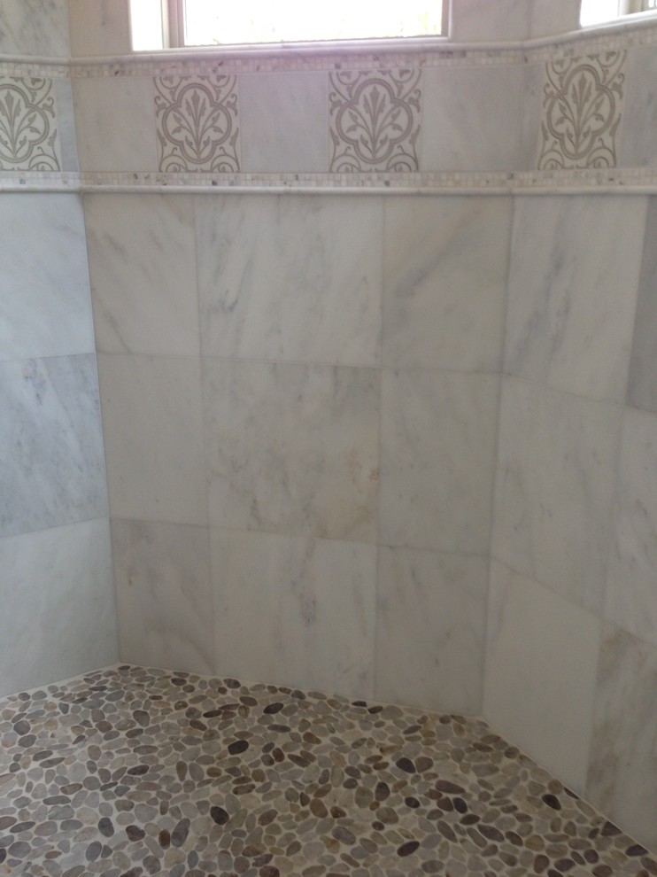 Cette photo montre une salle de bain principale chic avec une douche ouverte, un carrelage de pierre et un sol en galet.