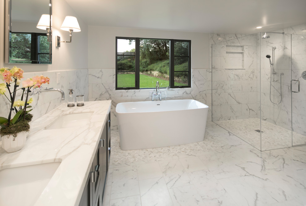 Inspiration for a large transitional master white tile and marble tile marble floor and white floor freestanding bathtub remodel in Santa Barbara with shaker cabinets, black cabinets, white walls, an undermount sink, marble countertops and a hinged shower door