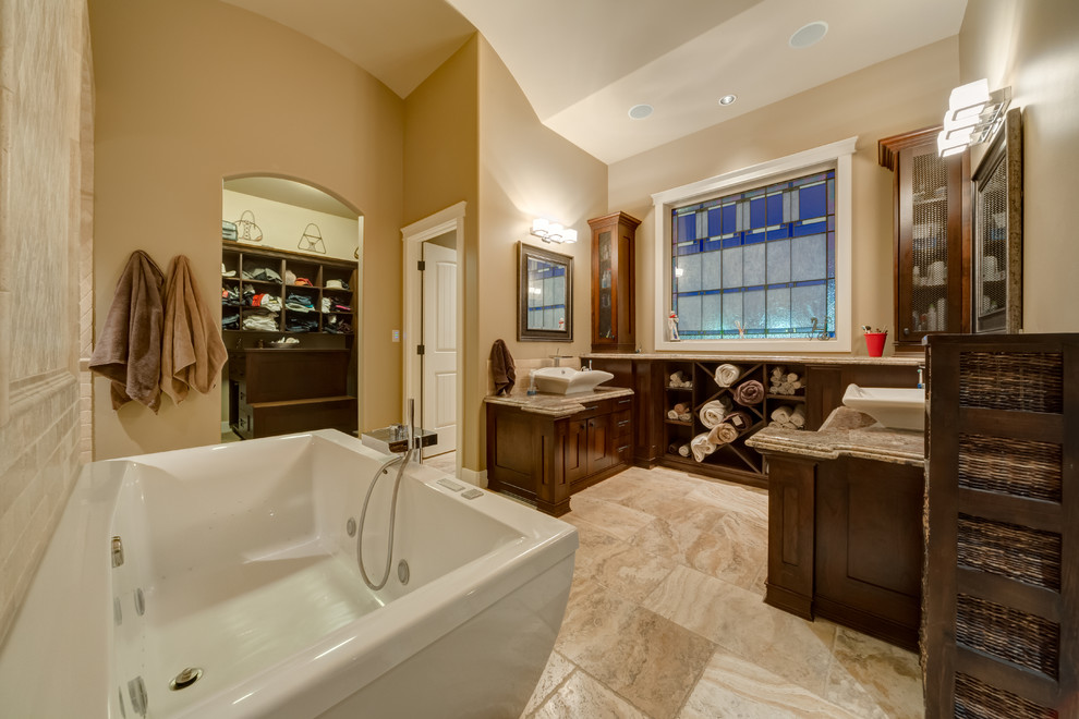 Diseño de cuarto de baño rectangular tradicional con lavabo sobreencimera, armarios estilo shaker, puertas de armario de madera en tonos medios, bañera exenta y baldosas y/o azulejos beige