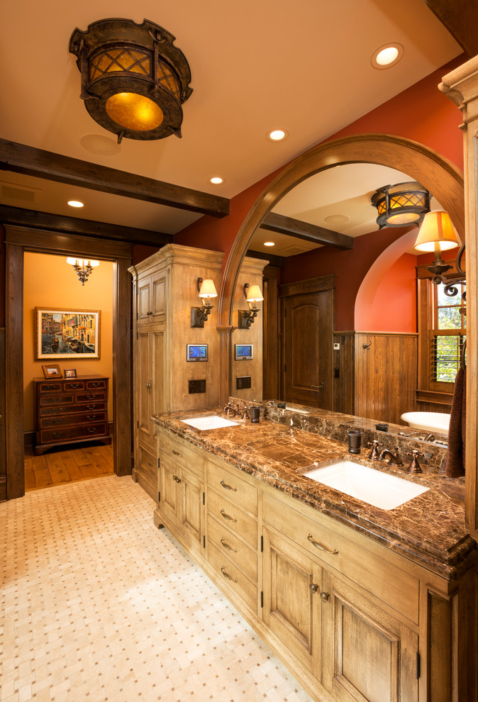 Klassisk inredning av ett stort en-suite badrum, med ett undermonterad handfat, skåp i mellenmörkt trä, beige kakel, röda väggar, granitbänkskiva, luckor med infälld panel och ett fristående badkar
