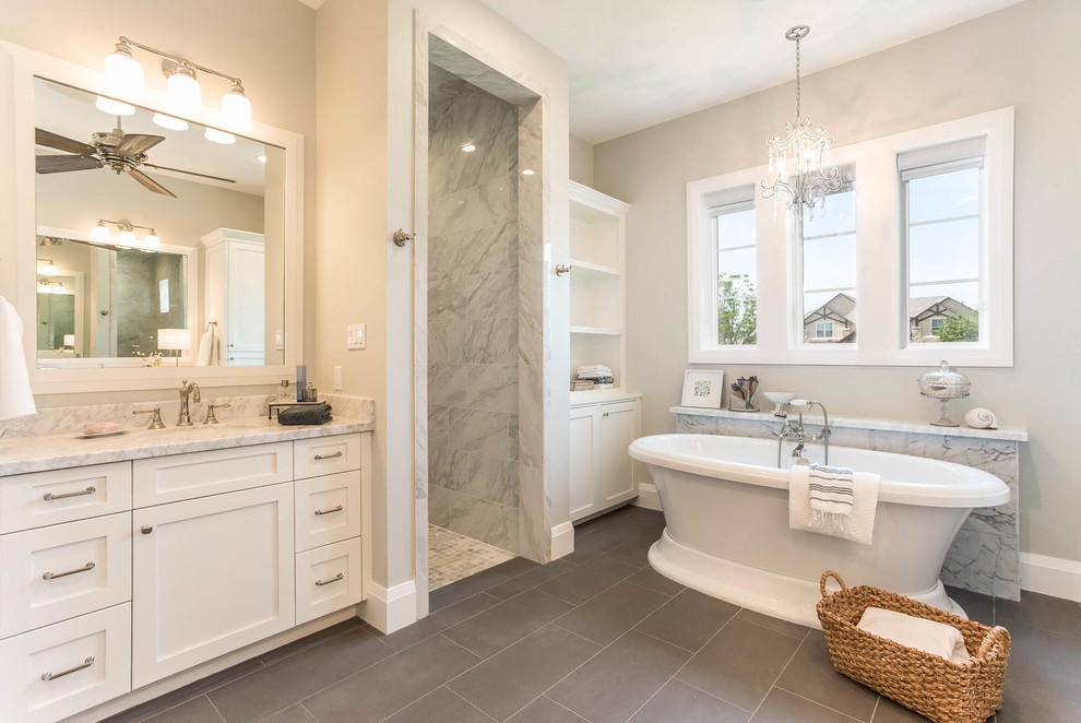 Идея дизайна: главная ванная комната в стиле кантри с белыми фасадами, отдельно стоящей ванной, открытым душем, серой плиткой, мраморной плиткой, бежевыми стенами, накладной раковиной, мраморной столешницей, коричневым полом и открытым душем