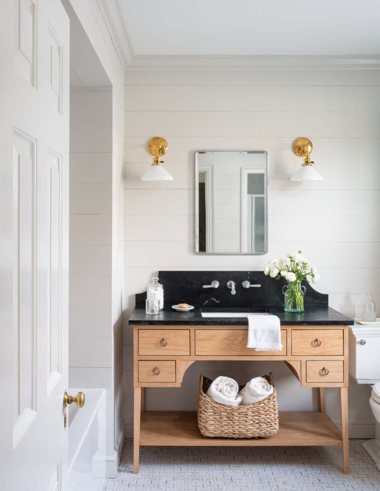 Exempel på ett mellanstort svart svart en-suite badrum, med en toalettstol med separat cisternkåpa, beige väggar, mosaikgolv, ett undermonterad handfat, bänkskiva i täljsten, släta luckor, skåp i ljust trä, ett badkar i en alkov och grått golv