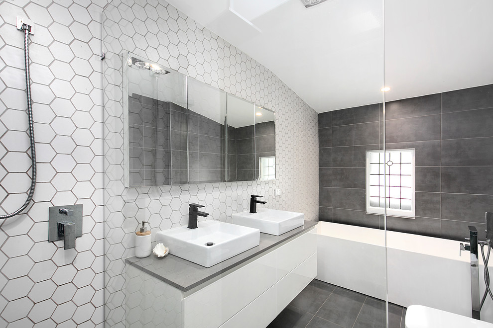 Design ideas for a modern ensuite bathroom in Sydney with white tiles, ceramic tiles, flat-panel cabinets, white cabinets, a built-in bath, grey walls, a vessel sink, solid surface worktops, an open shower and grey worktops.