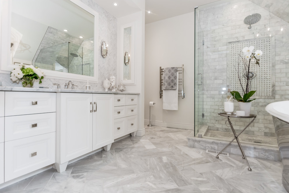 Medium sized traditional ensuite bathroom in Toronto with freestanding cabinets, white cabinets, a freestanding bath, an alcove shower, white tiles, marble tiles, white walls, marble flooring, a submerged sink, marble worktops, grey floors and a hinged door.