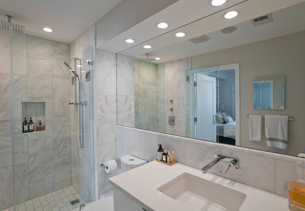 Inspiration for a small modern ensuite bathroom in DC Metro with flat-panel cabinets, white cabinets, an alcove shower, a one-piece toilet, white tiles, marble tiles, white walls, marble flooring, a submerged sink, engineered stone worktops, white floors, a hinged door and white worktops.